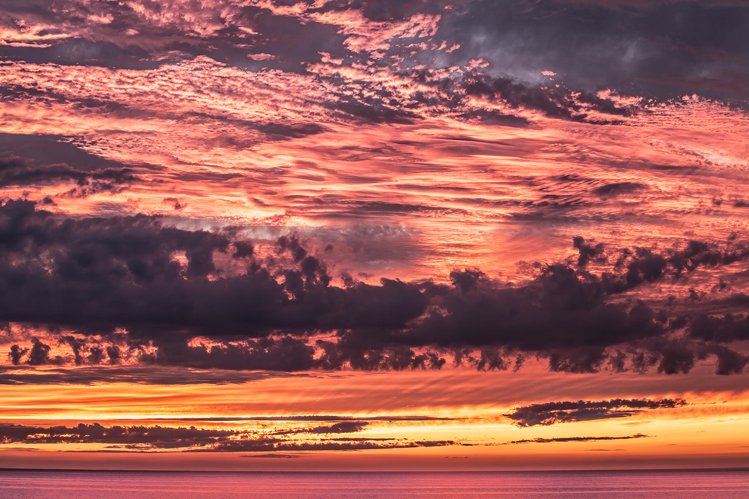 Prachtige roodgloeiende lucht bij zonsondergang boven de Noordzee met dramatische wolkenformaties.