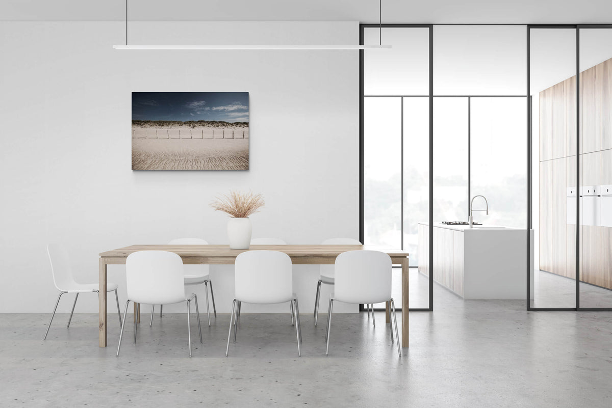 Groot canvas van het rustige strand van Knokke met houten paaltjes en zandduinen, formaat 120x80cm, in een elegant interieur.