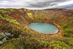 Kerið krater met turquoise water en kleurrijke rotslagen, omringd door weelderige groene begroeiing in IJsland.