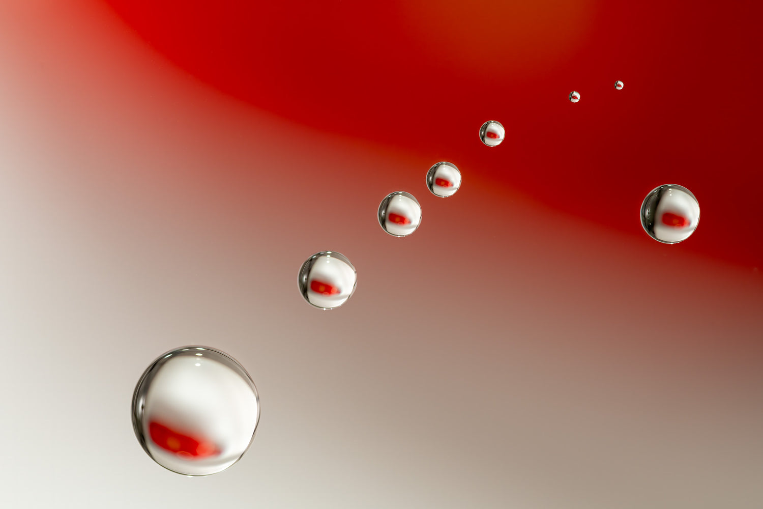 Abstracte afbeelding van zwevende waterdruppels op een subtiele rode achtergrond, met reflecties en een warme uitstraling.