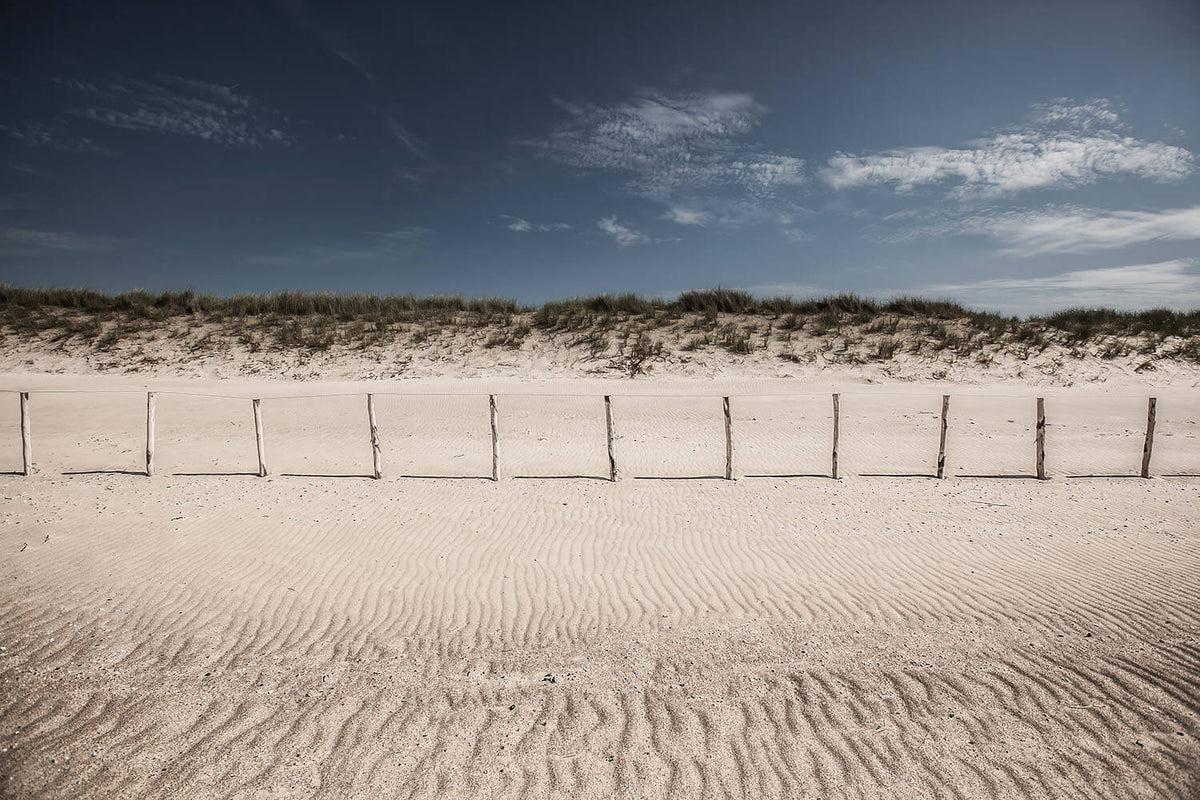 Uitgestrekt strand met houten paaltjes en duinen in Knokke aan de Noordzee.