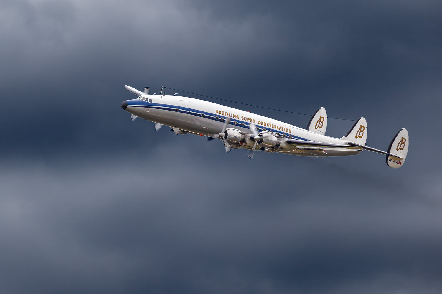Lockheed Super Constellation in de lucht tegen een bewolkte achtergrond, onderdeel van de Breitex Decoratiecollectie, ideaal voor liefhebbers van luchtvaartgeschiedenis.
