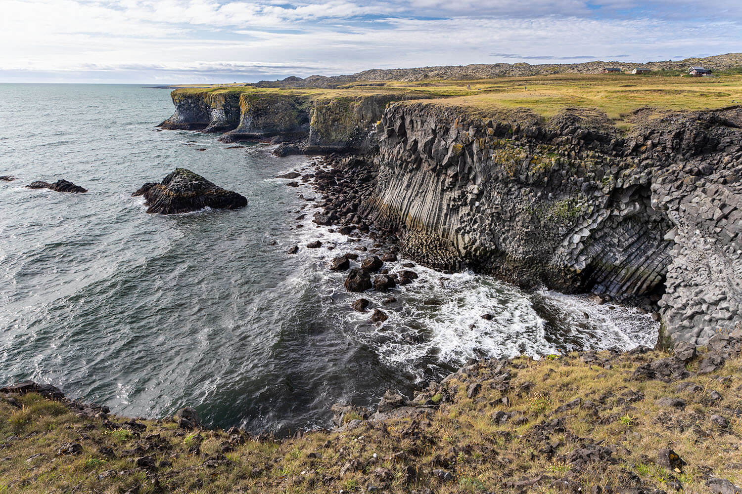Ruwe basaltrotsen aan de kust van IJsland, omringd door de golven van de Atlantische Oceaan.