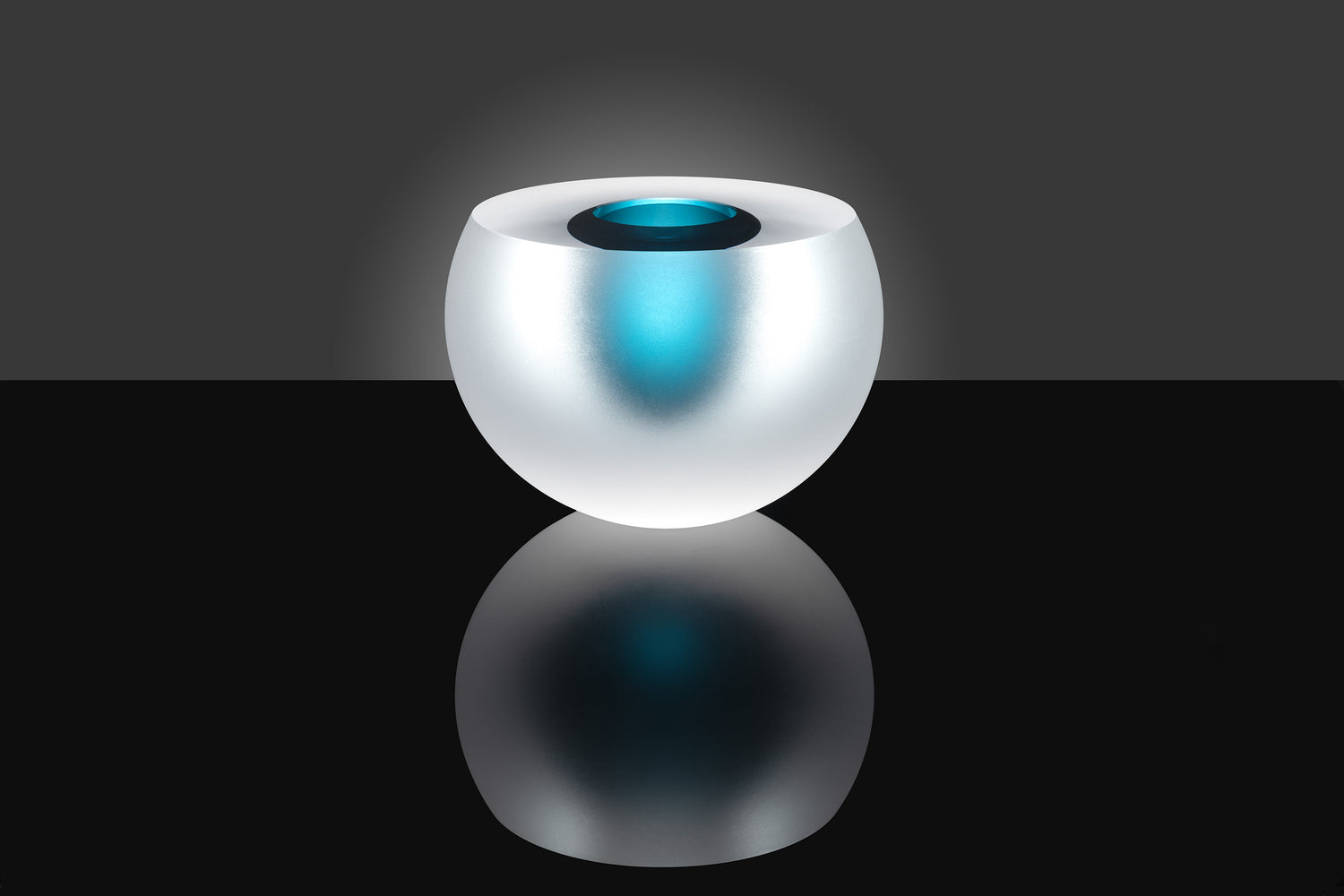 Glazen kunstobject "Dubbel Bubble" door Anna Torfs met een subtiele blauwe gloed, minimalistisch weergegeven op een zwarte achtergrond.