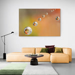 Monumentale afbeelding van waterdruppels tegen een oranje achtergrond, formaat 180x120cm, als indrukwekkend kunstwerk.